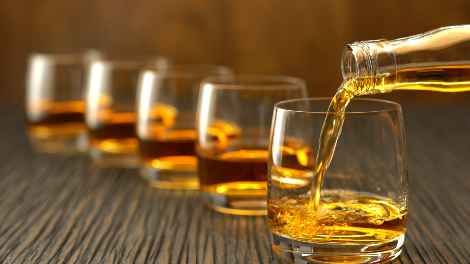 Pouring a scotch whiskey into glass on a wooden table